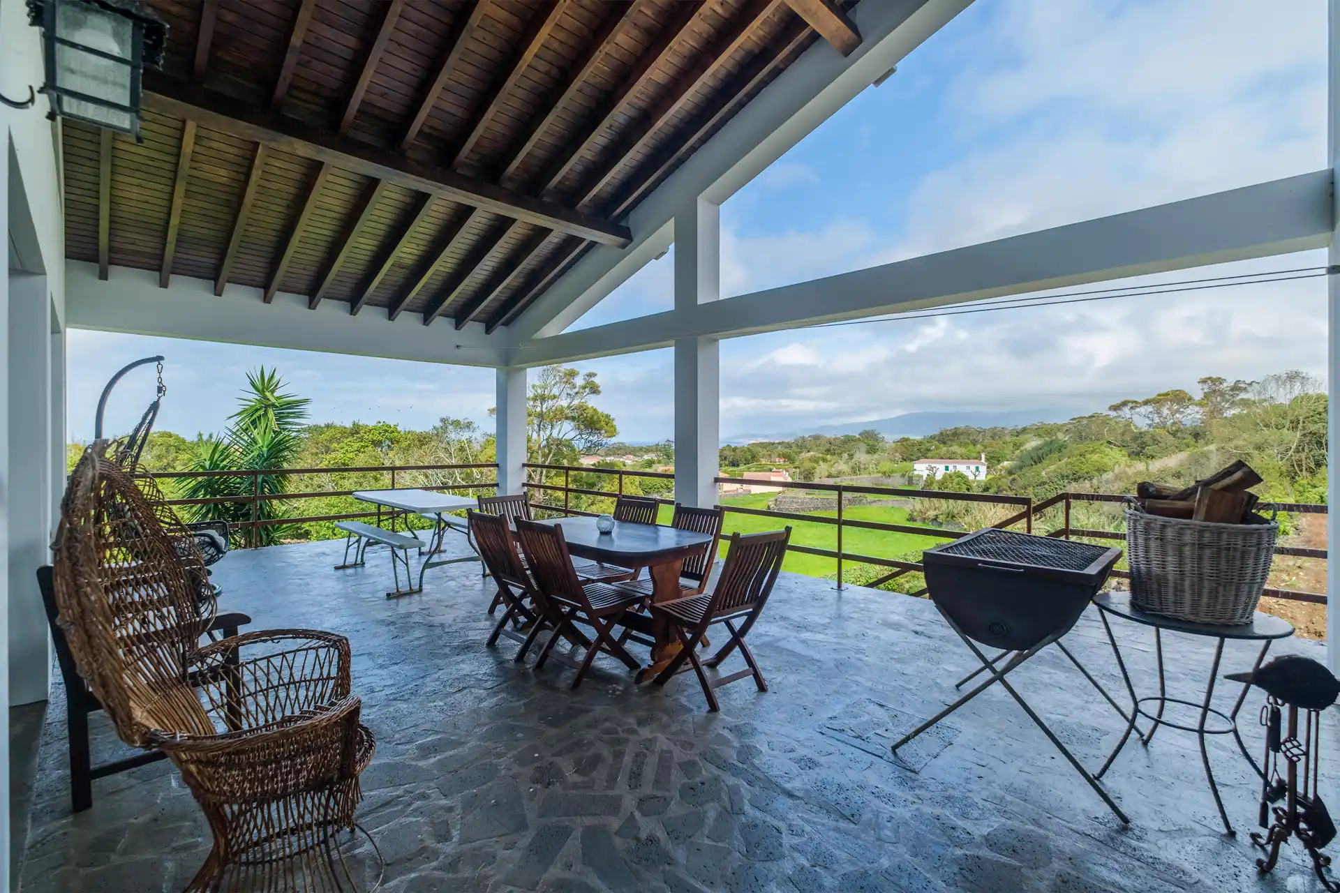 Covered terrace with BBQ and dining table at Casa das Hotências