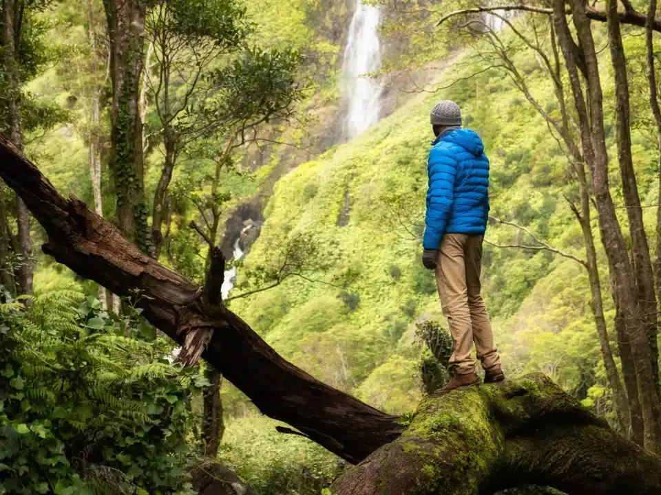 Caminhante a admirar uma cascata num trilho dos Açores